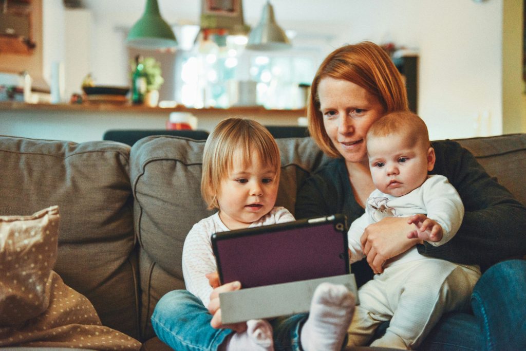 Mother and her two children play with an ipad.