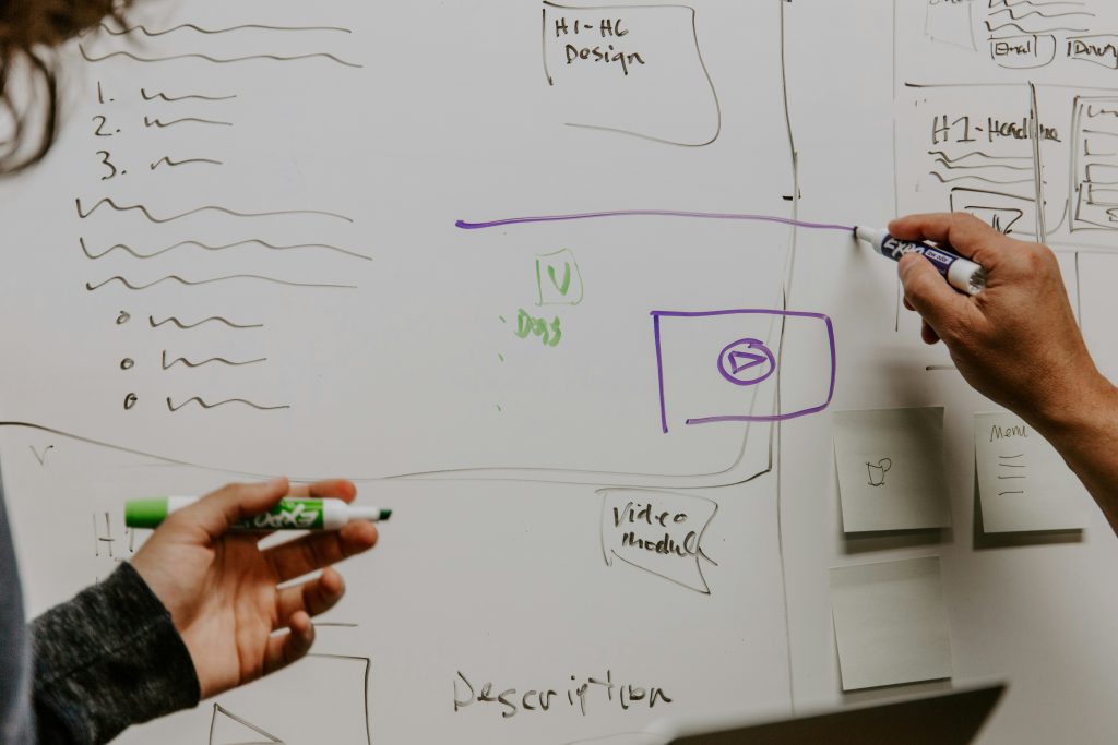 Two individuals actively writing on a whiteboard, engaged in a collaborative brainstorming session.