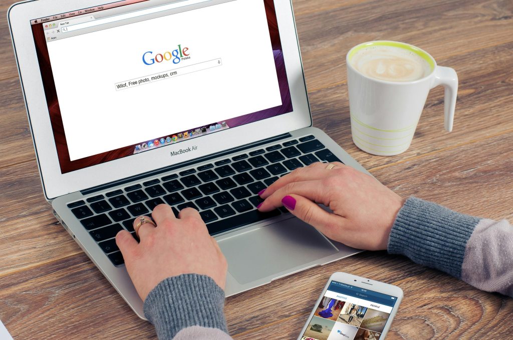 A person's hands on a computer keyboard, searching something on Google.