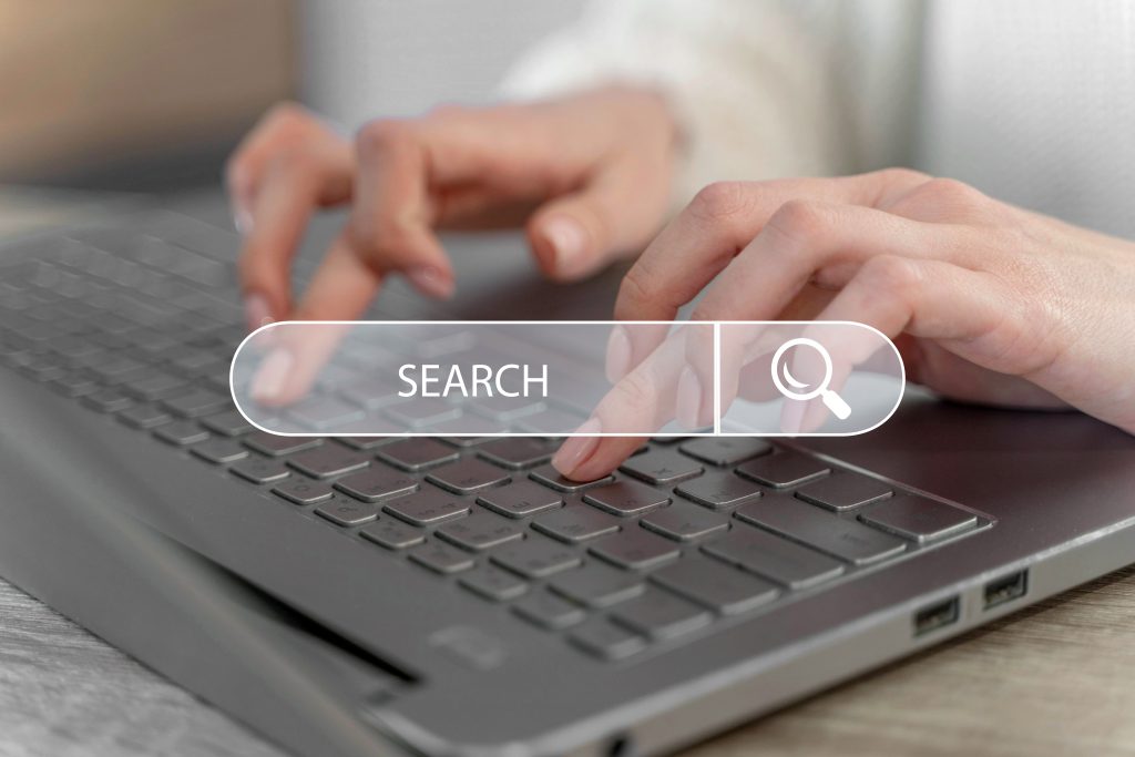 Hands typing on a computer keyboard with a search bar superimposed