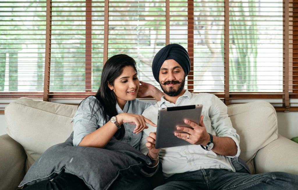 An Indian couple looking at their Ipad on the couch
