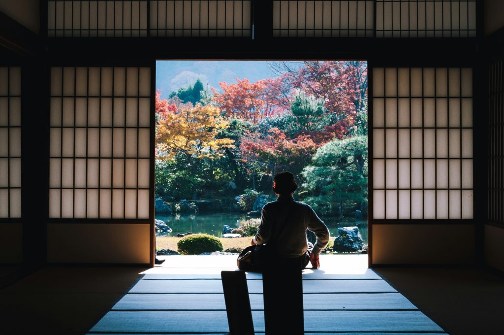 back of a japanese man sitting in front of a lake