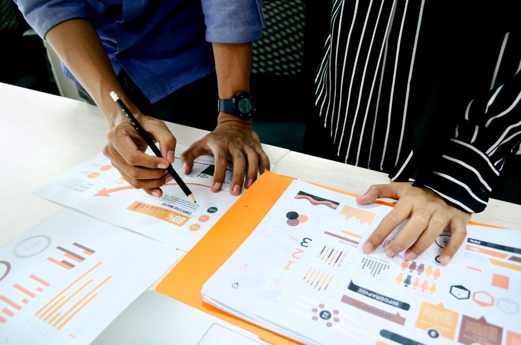 People looking at graphs on a table desk, just hands visible