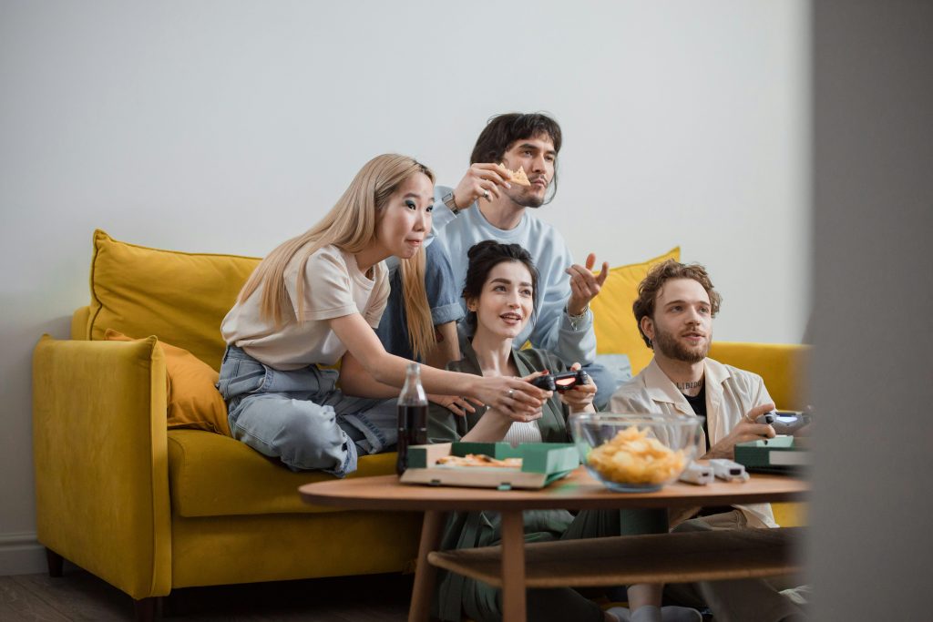 4 people gaming on a yellow couch