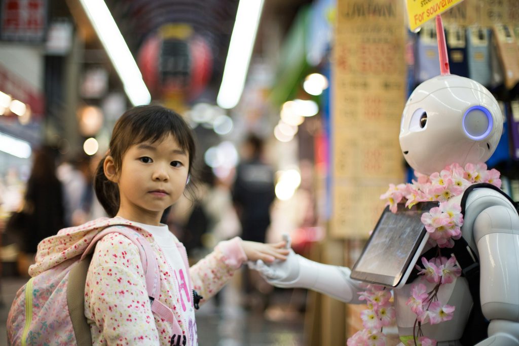 A little asian girl holding a robot hand